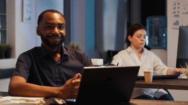 Mutlu başarılı yöneticinin portresi. Geceleri masa başında oturuyor. Ofiste kurumsal sunum üzerinde çalışıyor. Finansal web uygulaması ile profesyonel idari rapor oluşturmak için araştırma verileri planlanıyor.