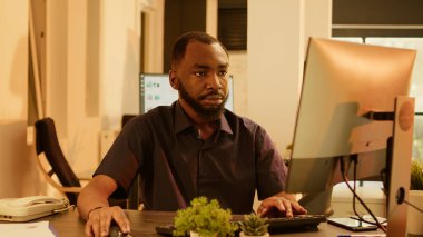 Bilgisayarla araştırma projesi üzerinde çalışan Afrikalı Amerikalı bir adam sunum yaratmak için veri raporunu analiz ediyor. Gün batımında ofiste yönetim evraklarını planlamak için beyin fırtınası yapmak.