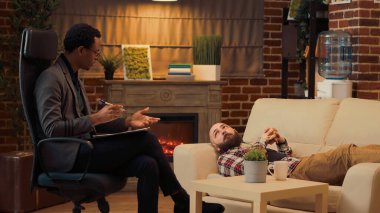 Afro-Amerikalı terapist mutsuz yetişkinleri dinleyip kanepeye uzanmış problemler hakkında konuşuyor. Psikoterapi seansında tavsiye vermek için danışmanlık yapıyorum. Üçayak atışı.