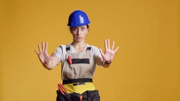 Portrait of construction worker doing stop sign with palm, advertising dont pass and finish gesture in studio. Female contractor showing timeout end symbol after working on refurbishment.