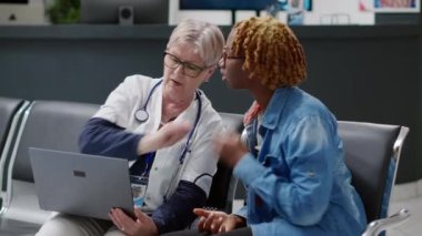 Dizüstü bilgisayarda genç bir kadına hastalık teşhisi koyan kıdemli bir doktor, tıp merkezi lobisindeki sağlık hizmetleri danışmanlığında tedaviyi açıklıyor. Klinikte check-up randevusu alıyorum..