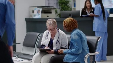 Eski pratisyen hekim hasta ile görüşmede notlar alıyor. Afro-amerikalı bir hastayla hastane bekleme odasında sağlık kontrolü yapıyor. Doktor ve kadın teşhisten bahsediyor..