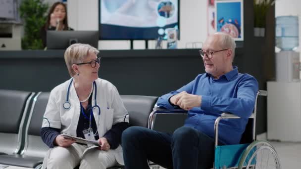 Lékař Radí Starému Muži Vozíku Ošetřovatelem Navštěvuje Prohlídku Nemocniční Hale — Stock video