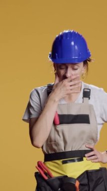 Dikey video: Çalışmadan sonra esneyen yorgun ve yorgun bir kadının portresi, stüdyoda kendini yorgun ve sıkıntılı hissediyor. İnşaatçı uyuyakalıyor ve çok çalışıyor, reklam yapıyor ve...
