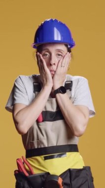 Dikey video: İnşaatta çalışan uykulu yorgun kadın portresi, inşaattan sonra uyuyakalmak ve kendini yorgun hissetmek. Stüdyoda tadilat için çalışan çok çalışan, sıkıntılı bir kadın..