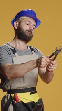 Dikey video: İnşaatçı yenileme projesinde çelik anahtarla çalışırken, inşaat ve onarım için paslanmaz anahtar kullanıyor. Erkek müteahhit yenileme işi için kıskacı çeviriyor.