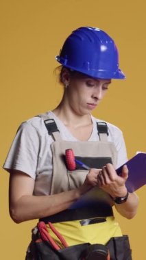 Dikey video: Not alan inşaat işçilerinin portresi ve pano kağıtları üzerinde mimari ölçüm, yazı ve beyin fırtınası fikirleri. Kadın mimar yenileme projesi planlıyor..