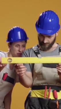 Dikey video: İnşaat işçileri düz yüzeyi ölçmek için su seviyesi araçları kullanarak, yeniden inşa üzerinde çalışarak dengeli ve dengeli hale geliyorlar. Sabit ölçüm için kullanılan bank seviyesi aracı tutuluyor.