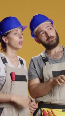 Dikey video: Yıkımı planlamak, endüstriyel mühendislik üzerinde çalışmak ve ölçüm yapmak için beyin fırtınası yapan bir ekip. İnşaat işçileri inşaat alanında kasketli inşaat planlıyorlar..