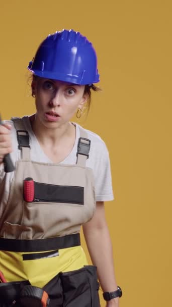 垂直录像 被授权的女建筑商在镜头前用锤子表现危险的形象 用打击工具进行威胁和愤怒 拿着大锤的暴躁好斗的女人 — 图库视频影像