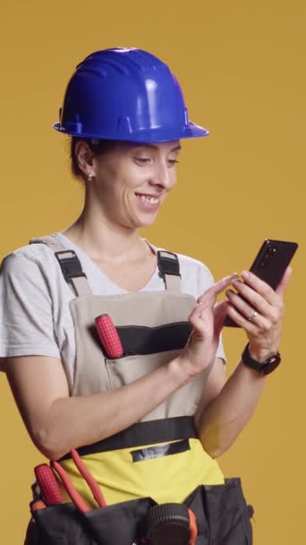 垂直ビデオ インターネットを閲覧し 改装されたインスピレーションを見つけるためにスマートフォンを使用して女性エンジニアの肖像画 解体作業によって権限を与えられる非典型的な仕事感覚を持つ自信者 — ストック動画