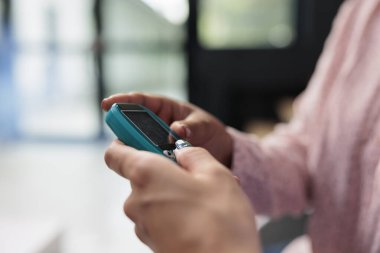 Glikometreyle glikoz ve insülin seviyesini ölçen tıbbi asistanı kapatın. Şeker hastalığı olan bir kadın için şeker testi yapın. Hastanın klinik lobisinde muayene randevusu var..