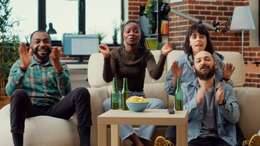 Çeşitli insanlar televizyonda futbol maçı izliyor ve favori futbol takımıyla şampiyonluğu kazanmak için tezahürat yapıyorlar. Spor taraftarları turnuvanın tadını çıkarıyorlar, şampiyonluk maçında destek veriyorlar. Üçayak atışı.