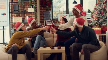 Çok ırklı bir grup insan, kış tatilini kutlamak için kadeh tokuşturuyor. Noel Baba şapkası takmak ve Noel arifesinde ofiste alkol içmek..