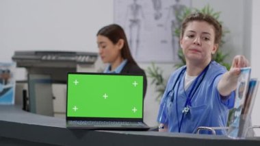 Hemşire ve resepsiyonist resepsiyonda dizüstü bilgisayarla çalışıyor. Pc ekranında boş krom anahtar şablonu ve izole edilmiş model arkaplan görüntüsü ve kopyalanma alanı kullanılıyor.
