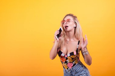 Sevimli genç kadının telefonunu Studio üzerinde sarı arka plan üzerinde şarkı