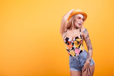 Stüdyoda şapkalı ve güneş gözlüklü seksi sarışın bebek.