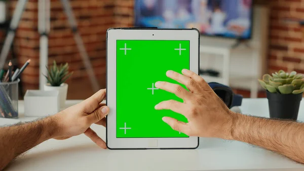 Office employee using digital gadget with greenscreen template, vertically holding portable tablet with isolated display. Working with blank chroma key background and mock up screen. Close up.