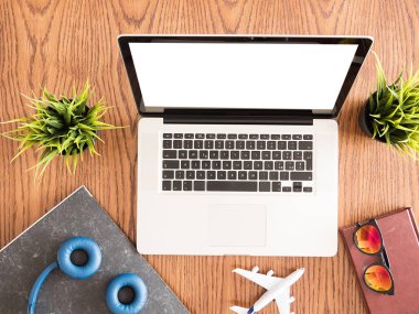 Gezgin işadamı dizüstü ahşap masa üstü bilgisayarda vie, güneş gözlüğü, kulaklık, kitap