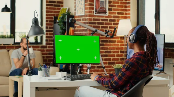 Office worker analyzing greenscreen template on monitor, working with isolated mock up background at desk. Using blank chroma key display with copy space on personal computer at home.