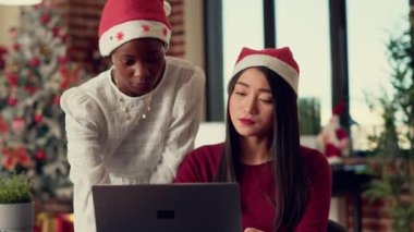 Mevsimsel süslemeler ve noel ağacı ile süslenmiş bir vaziyette ofiste çalışan çok ırklı insanlardan oluşan bir ekip. Noel Baba şapkalı kadınlar kış tatilinde takım çalışması yapıyorlar..