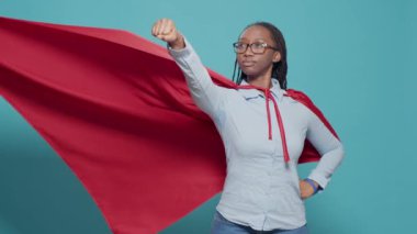 Portrait of superhero with flying red cape on camera, posing as action cartoon character with costume and cloak. Showing motivation and strength in studio, positive and powerful.