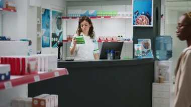 Hastalıklı ve reçeteli tedavi gören insanlara yardım etmek için vitamin kutularını işaretleyen mutlu bir sağlık çalışanı. Eczane tezgahında çalışan ve ilaç ve ürünlere bakan eczacı..