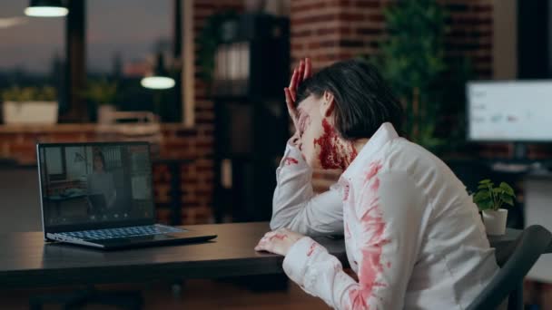 令人毛骨悚然的愤怒僵尸在网上视频会议与亚洲同事 由于与公司同事的网络视频通话 令人头痛的食人脑的行尸走肉造成了流血的伤口 — 图库视频影像