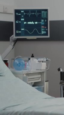 Dikey video: Kalp atış hızı monitörlü boş hastane koğuşu ve sağlık ve iyileşme için yatak. Acil serviste kimse yoğun bakım için tıbbi ekipman kullanmıyor. Aletlerle yeniden canlandırma odası