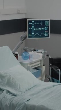 Dikey video: Sağlık ekipmanları ve kalp atış hızı monitörüyle hastane koğuşunda yatağı hazırlayan hemşire. Tıbbi asistan hasta için acil servis hazırlıyor. Yeniden canlandırma alanındaki kadın