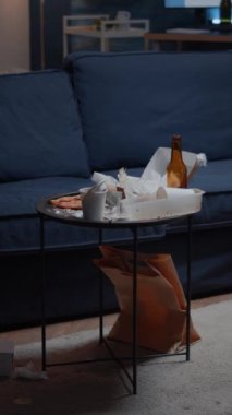 Dikey video: dağınık oturma odasındaki bira şişeleri ve pizza masasında kimse yoktu, yemek artıkları yere atılmıştı. Terk edilmiş, terk edilmiş, çöpleri olan yalnız bir kadının dairesi.