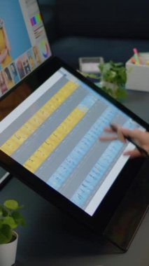 Dikey video: Stüdyoda dokunmatik ekrandaki yazılımı kapat. Fotoğraf tasarımı için kurgu uygulaması üzerinde çalışan bir fotoğrafçı. Resim düzenleyicisi resim üzerinde grafik tableti kullanarak rötuş yapıyor.