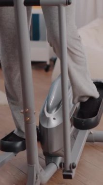 Dikey video: Yaşlı yetişkin sabit bisiklet üzerinde bisiklet egzersizi yapıyor. Bisiklet üzerinde bisiklet aktivitesi yapmak için statik kardiyo makinesiyle yaşlı kadın eğitimi. Form ve spor malzemelerini kullanan kıdemli kişi