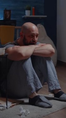Dikey video: Depresyon, yalnızlık hissini hissettiğinde ve yerde oturup acı içinde ağlayarak acı çektirdiğinde bipolar bozukluk geçiren olgun, travmalı bir adam.