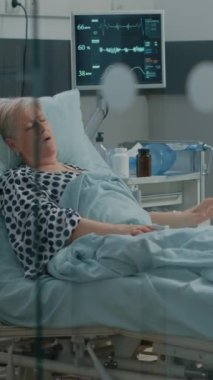 Dikey video: Coronavirus hastası salgın sırasında karantina bölgesindeki uzmanlardan tıbbi yardım istiyor. Doktor ve hemşire emekli kadına virüs belirtileri konusunda yardım ediyorlar..