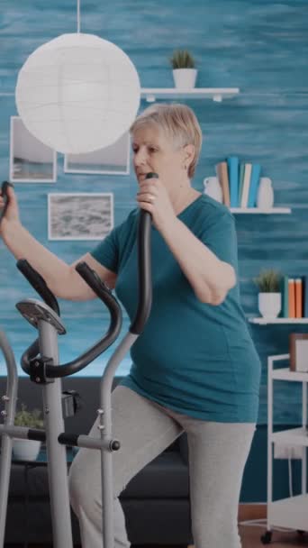 Vertical Video Mature Woman Using Stationary Bicycle Physical Exercise Home — Stock Video