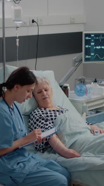 Pionowe Wideo Pielęgniarka Pomaga Starszemu Pacjentowi Chorobą Łóżku Asystent Medyczny — Wideo stockowe