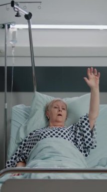 Dikey video: Doktor ve hemşire yatakta ağır nefes alan hasta için oksijen tüpü ve oksimetre kullanıyor. Tıbbi ekip, yaşlı kadının solunum sorununu ekipman ve aletlerle tedavi etmesine yardım ediyor..