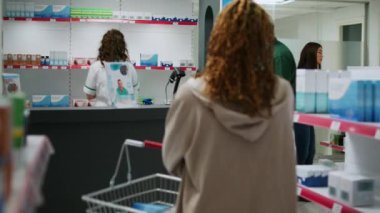 Reçeteli ilaç için kardiyoloji hapı alan kıdemli bir müşteri eczacıyla eczane reyonunda sağlık tedavisi hakkında konuşuyor. Yaşlı müşteri ilaç ve vitamin satın alıyor.