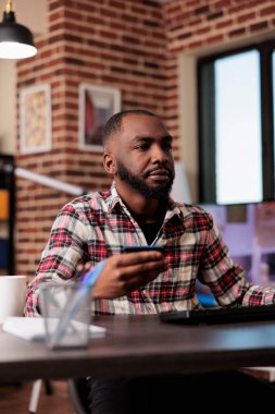 Serbest çalışan bir erkek bilgisayar alışverişi yapıyor, elektronik ödeme işlemleri için kredi kartı kullanıyor. Perakende satış mağazasının internet sitesinden indirimli satın alma, evden uzaktan çalışma.