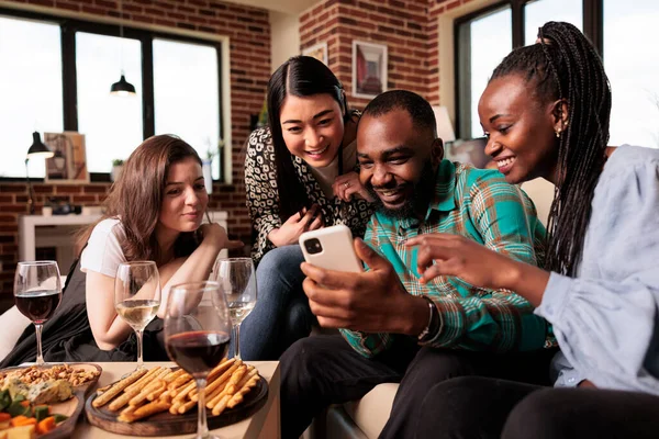 年轻的非洲裔美国夫妇在手机屏幕上向不同种族的女性展示照片 每个人都面带微笑 多元文化团体的朋友们 看着手机 — 图库照片