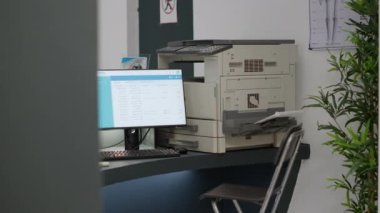 Sağlık merkezindeki resepsiyonda hastalara tıbbi destek vermek için bilgisayardan randevu alınıyor. Rapor kağıtları ve kontrol formlarıyla boş hastane kayıt masası. El kamerasıyla..