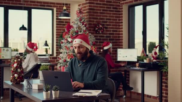 Mężczyzna Pracownik Rozmawiający Przez Wideokonferencję Internetową Noszący Kapelusz Mikołaja Uroczystym — Wideo stockowe