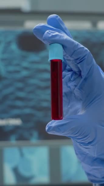 垂直ビデオ 科学研究所で血液や赤い液体で掃除機を保持手袋で手を閉じてください 研究室のガラス製品の溶液と化学的透明ツール バイオテクノロジー研究 — ストック動画