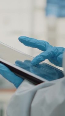 Dikey video: Oral klinik dolabındaki modern tablette diş röntgeni kullanılarak elde kapatın. Radyografi ve tarama teknolojili stomatoloji asistanı hasta için diş modelini inceliyor.