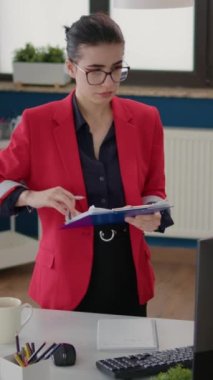 Dikey video: Satış istatistiklerini analiz eden yönetici yardımcısı, yeni iş stratejisi için mali belgelere bakıyor. Başlangıç ofisinde kadın çalışan planlama gelişimi.