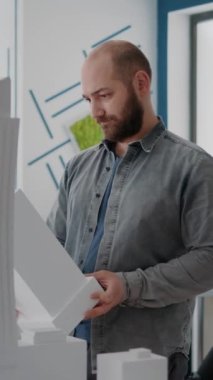 Dikey video: Mimarın mimari proje ve yapı yaratmak için elinde tuttuğu yapı modelinin portresi. İnşaat planı ve kentsel mimari tasarımı için maquette düzenine bakan insan müteahhiti.