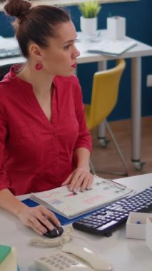 Dikey video: Şirket muhasebecisi finansal belgeler üzerine notlar alıyor, satış raporlarını analiz ederek iş geliştirme planı yapıyor. Proje araştırmaları için pazarlama istatistikleri kullanan ofis çalışanı.