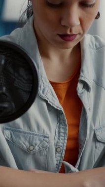 Dikey video: İnternet podcast programı sunucusu kameraya bakarken stüdyoda oturuyor. Genç sosyal medya içeriği yaratıcısı dijital izleyiciler için video kaydetmeye hazırlanıyor. Stüdyo çekimi