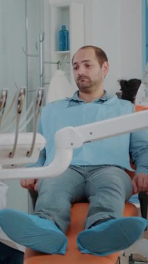 Dikey video: Stomatolog ortodontik alet ve aletlerle diş muayenesi yapıyor, diş ağrısı olan hastayı tedavi ediyor. Ağız sağlığı muayenesinde matkap ve dişçilik ekipmanı kullanan diş hekimi.